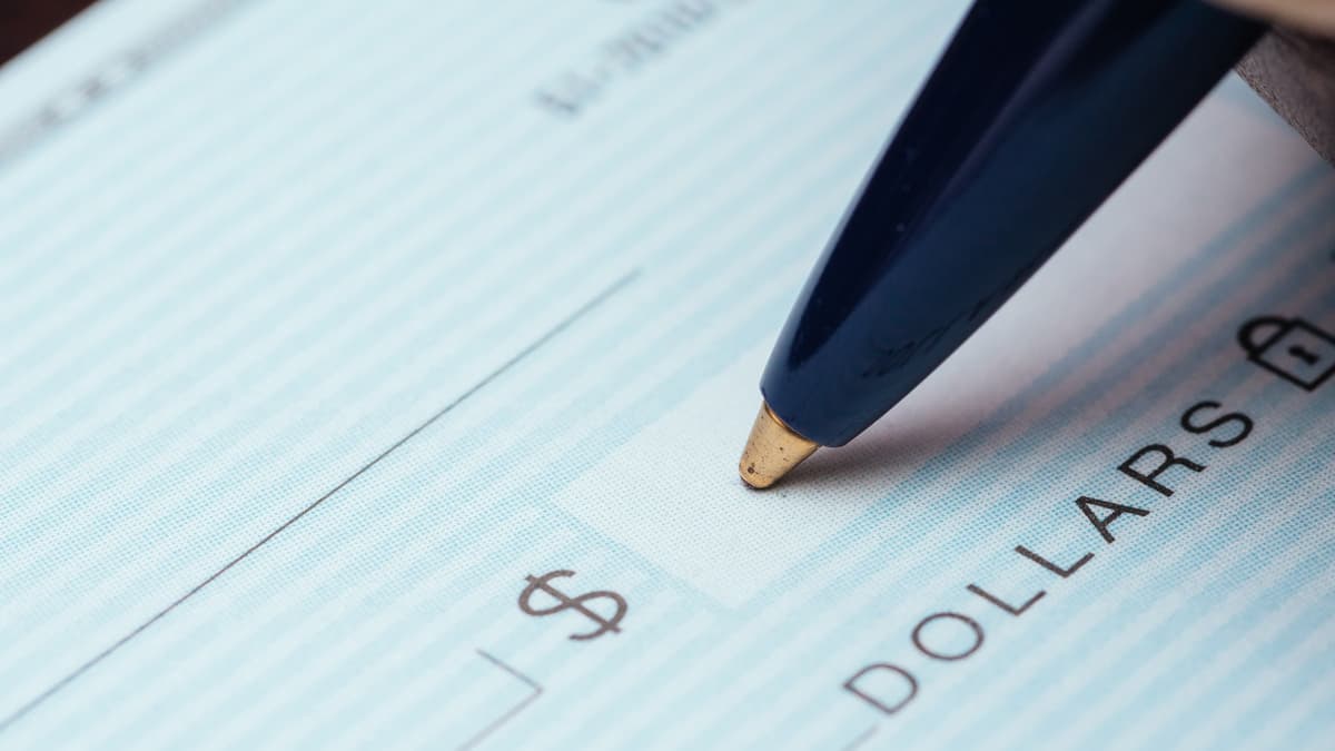 Pen writing on paycheck showing dollar sign claiming exempt status on Form W4