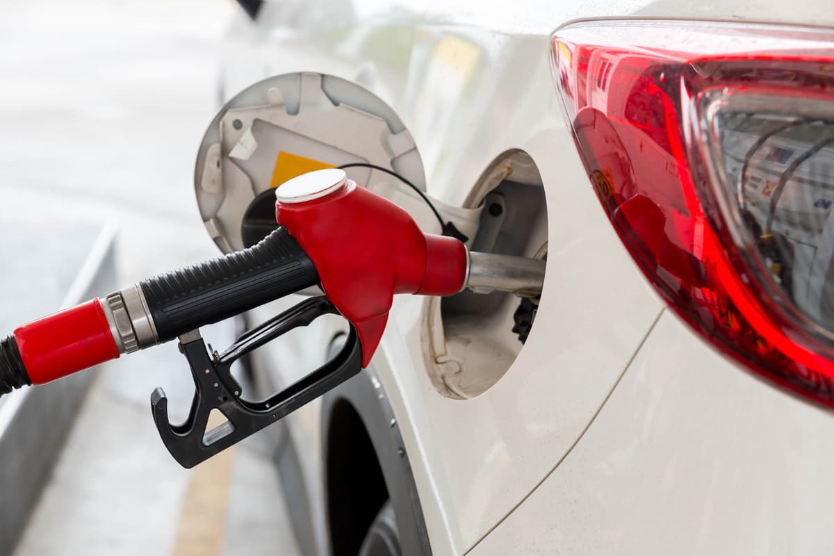 white car getting gas from red pump